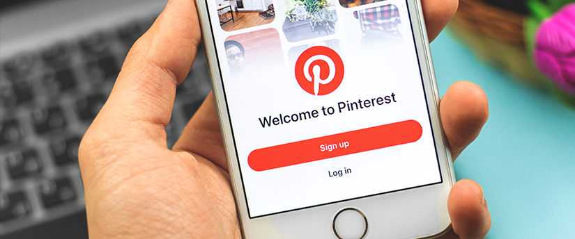 A person holding a smartphone, with the Pinterest sign-in page open, ready to access the platform's features and content.