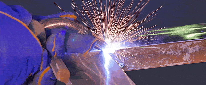 Welding process with a torch, sparks flying, metal melting, protective gear worn by worker.