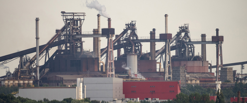 An industrial factory featuring multiple chimneys and smoke stacks, releasing smoke, symbolizing manufacturing processes.