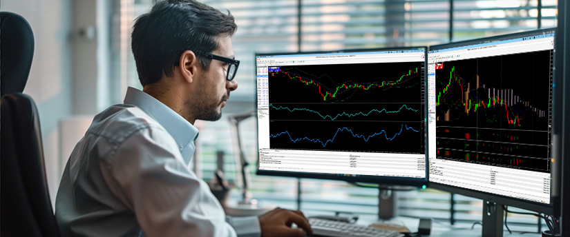 Man analysing MT4 charts on dual monitors, showing technical indicators and live market price movements.