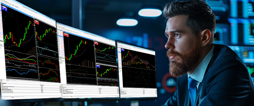 A focused man in a suit monitors financial data on multiple computer screens displaying colorful stock market charts in a dimly lit office, analyzing Forex market timing and trading opportunities.