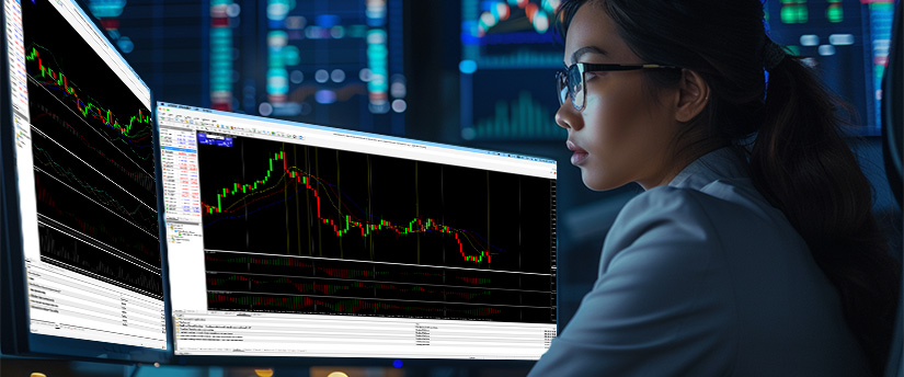 In a dimly lit room, a focused woman in glasses analyzes two computer screens displaying stock charts, concentrating on indicators of stop loss hunting and market liquidity.