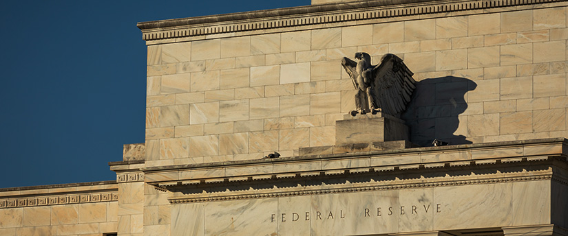 Exterior marble facade of the Eccles Federal Reserve building showing the sculpted eagle casting a shadow above the carved "FEDERAL RESERVE" text, illustrating Federal Reserve Rate Cut Expectations 2026.